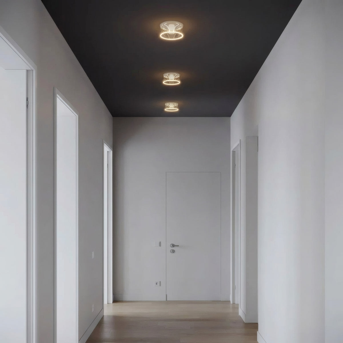 Tre lampadine LED donut E27 in vetro trasparente allineate a soffitto in un corridoio essenziale