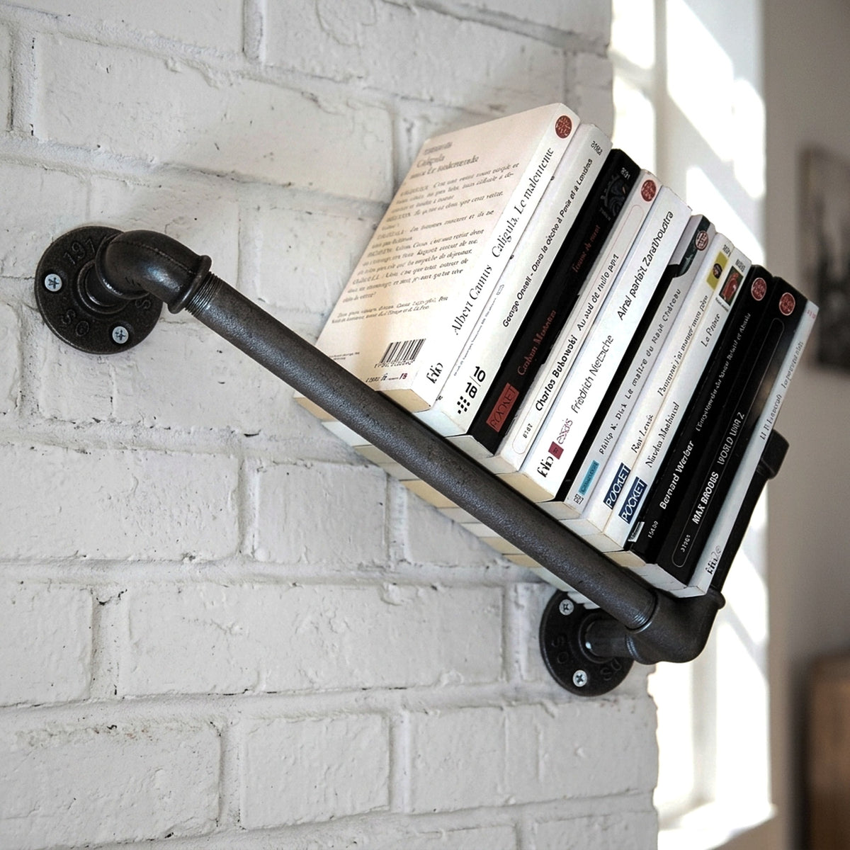 Libreria a parete in ghisa su muro di mattoni con libri, ambientazione loft