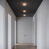 Tre lampadine LED donut E27 in vetro trasparente allineate a soffitto in un corridoio essenziale