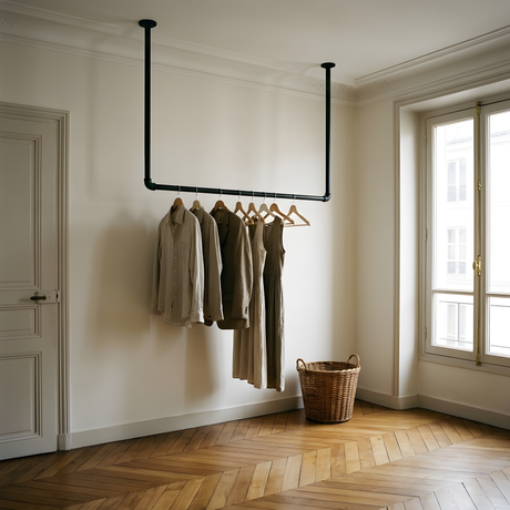 Appendiabiti da soffitto in tubo nero in un ingresso, un cappotto e una sciarpa appesi